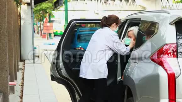 亚洲女人是关心帮助戴面膜保护老年人下车时防止病毒在空气中传播视频的预览图