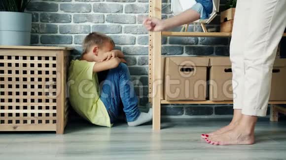 严厉的母亲惩罚男孩对坐在地板上哭泣的孩子摇指视频的预览图