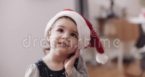 可爱的蹒跚学步的女孩戴着圣诞老人的帽子视频的预览图