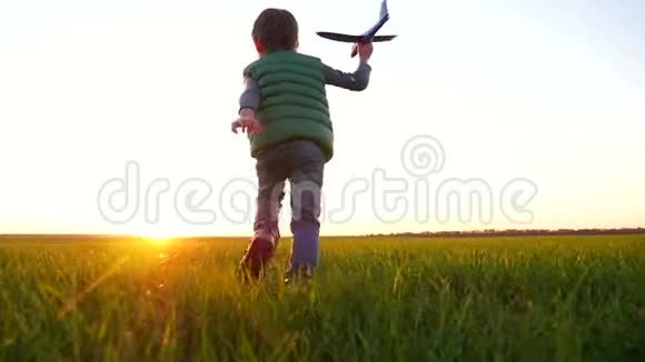 一个快乐的小男孩跑过一片绿色的草地向天空发射了一架飞机视频的预览图