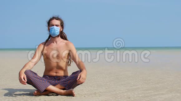 一个蒙面青年在海滩上沉思冠状病毒流行视频的预览图