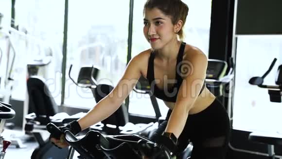 漂亮的亚洲女人在健身房骑着旋转自行车视频的预览图