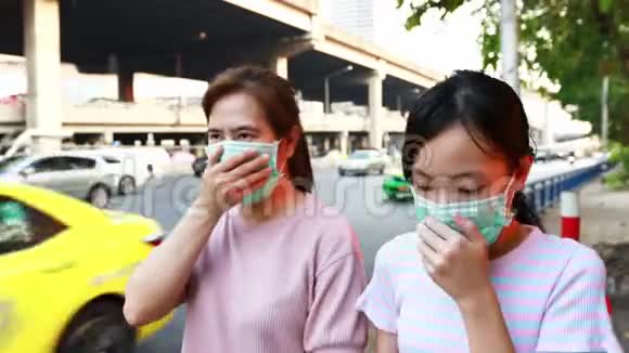 戴着卫生口罩的亚洲母女在户外行走对灰尘污染空气污染过敏PM25医疗保健病毒视频的预览图