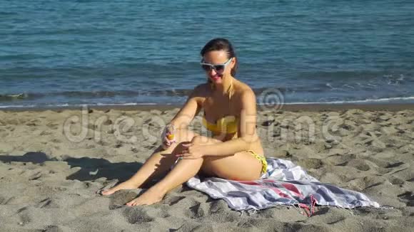 在沙滩上涂上润肤露的女人视频的预览图