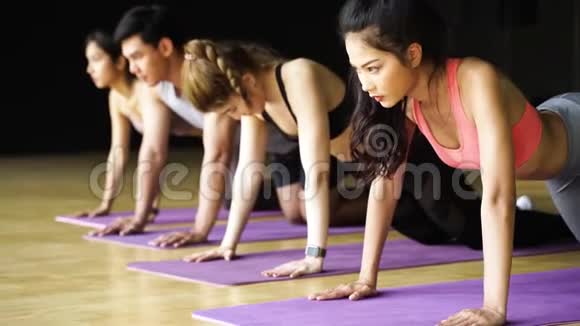 一群亚洲女人和男人在健美操课上做瑜伽垫上的俯卧撑练习年轻人在锻炼视频的预览图