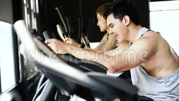 侧面观看迷人的亚洲女人和男人骑在旋转自行车在健身房年轻夫妇在锻炼身体视频的预览图