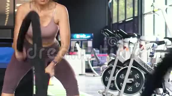 亚洲混合女性健美运动员在健身馆练习交叉配合运动的战斗绳索视频的预览图