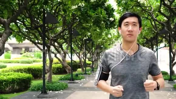 亚洲年轻人在公园听音乐时慢跑的慢动作视频视频的预览图