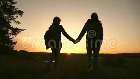 女人旅行牵着手在日落时穿过树林徒步旅行者女孩慢动作女孩旅行者去悬崖视频的预览图
