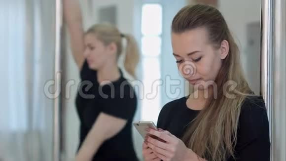 可爱的钢管舞女在锻炼和社交网络中休息时用手机而她的视频的预览图