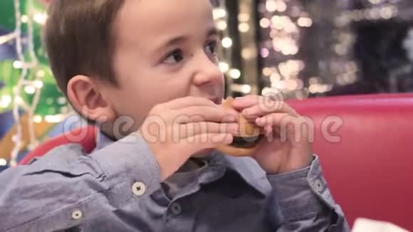 在沙发上的咖啡馆里吃汉堡的男孩视频的预览图