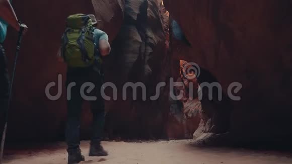 徒步旅行者在深洞斜坡峡谷中沿着一条带橙色岩石的沙河徒步旅行视频的预览图