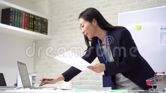亚洲女商人一边在办公室一边修改文件视频的预览图