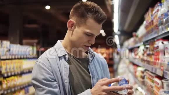 年轻人在超市里选择慢跑或酸奶油顾客在奶制品货架上选择产品视频的预览图