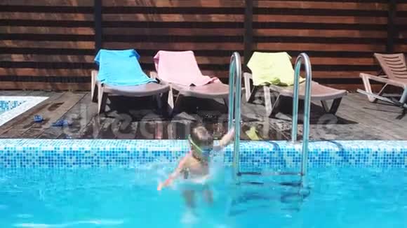 小男孩跳着跳进游泳池的水里在游泳池里学游泳的小男孩视频的预览图