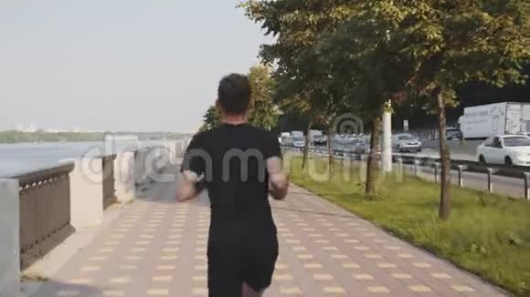 清晨穿着黑色T恤和运动短裤的年轻运动员沿着荒芜的长廊奔跑活泼好动的男人视频的预览图