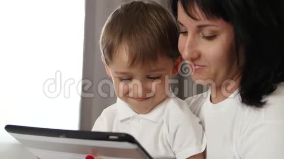 幸福的母亲和儿子的肖像母亲在平板电脑上使用一个孩子的发育申请视频的预览图