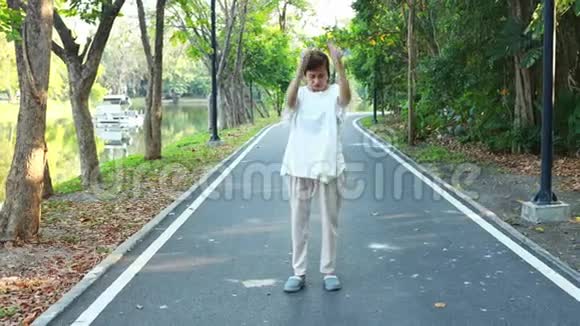 健康的亚洲老年妇女站直在街上散步锻炼时手臂上下摆动视频的预览图