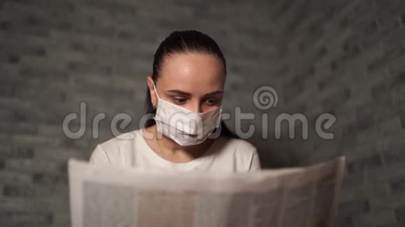 一个带着医疗面具的女人她听到的关于冠状病毒的消息来自报纸冠状病毒的流行视频的预览图