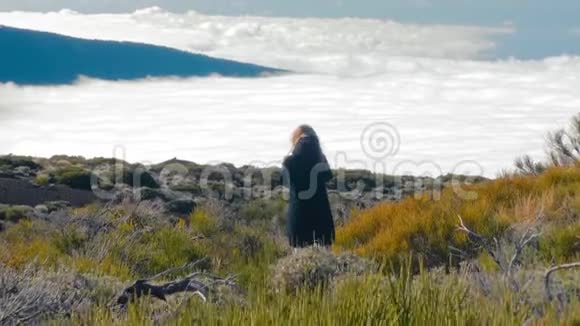 迷人的女人站在悬崖边山谷和森林之上有云海的美丽景观视频的预览图