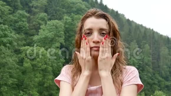 美丽悲伤的女孩站在夏天的雨中背景是覆盖着森林的山脉年轻时视频的预览图