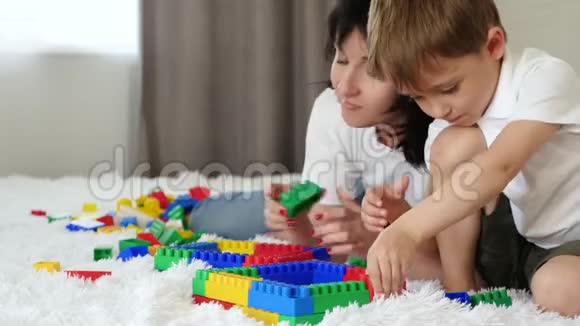 母亲和孩子躺在床上休息幸福的家庭玩Meccano彩色积木视频的预览图