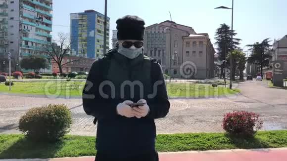 街上戴着口罩的男人在街上使用智能手机视频的预览图