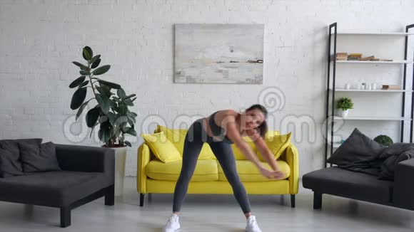 漂亮的年轻女子在房间里做腹部运动视频的预览图