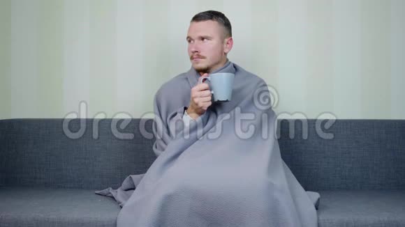 一个满身毯子的病人望着窗外喝着一杯热茶视频的预览图