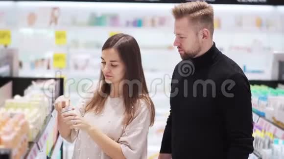夫妻在化妆品店里选择奶油女人打开罐子闻一闻视频的预览图