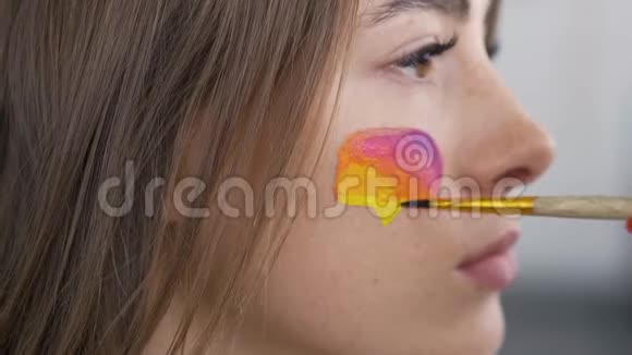 一位年轻漂亮女人的特写肖像艺术家在女孩脸上用社会媒体多色图标视频的预览图