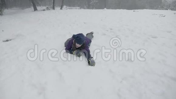 一个年轻的女孩爬过雪地假装挣扎直到她终于跪了起来视频的预览图