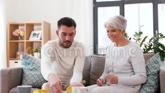 年长的母亲和成年的儿子在家吃蛋糕视频的预览图
