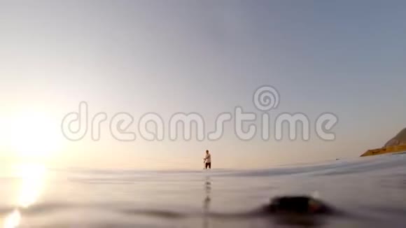 站起来的冲浪板上一个男人的日出剪影在宁静的海面上划船视频的预览图