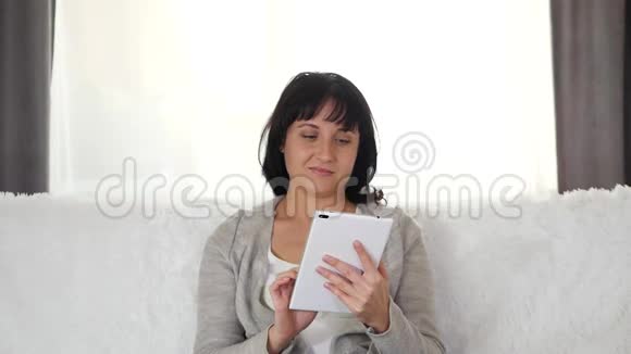 一个女人在家里用平板电脑工作小男孩玩捉迷藏闭上妈妈眼睛惊喜母亲和儿子视频的预览图