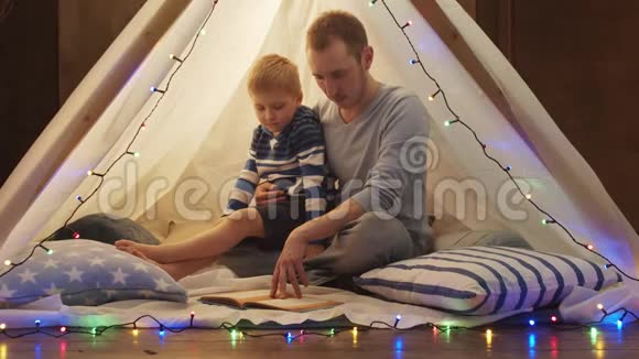 小男孩在家里的儿童帐篷里玩父亲在读童话快乐的白种人小孩在游戏室视频的预览图