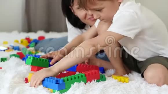 孩子和他的母亲在床上玩迷彩块幸福家庭的概念视频的预览图