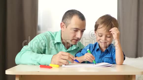 快乐的爸爸花时间和他的小儿子一起玩和画画视频的预览图