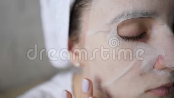 在女性脸上涂上保湿的白色面膜自然健康护理灰色背景特写视频的预览图