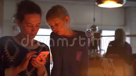 妈妈和女儿在智能手机上安装了一个新儿童应用程序视频的预览图