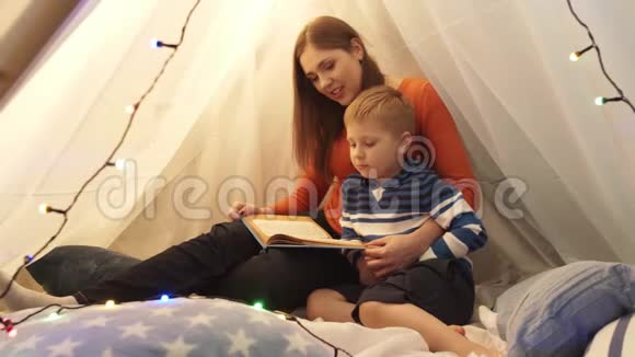 小男孩在家里孩子们的帐篷里玩妈妈在读童话书快乐的白种人小孩在游戏室视频的预览图