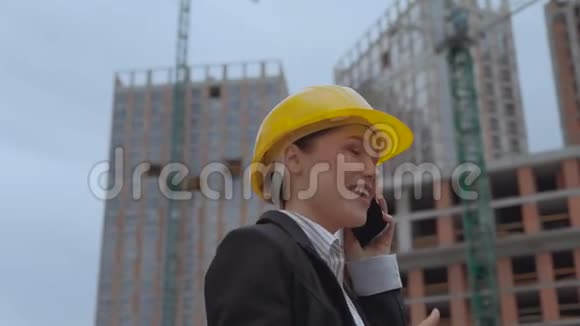 移动摄像头一个女人兴奋而愉快地在一个建筑工地的背景下打电话妇女视频的预览图