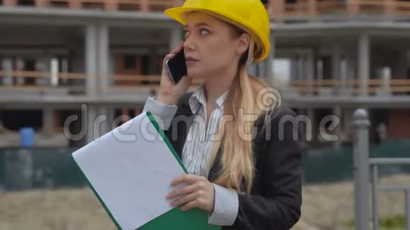 在建筑工地的背景下30岁的女工程师穿着西装在电话中交谈一个女人视频的预览图