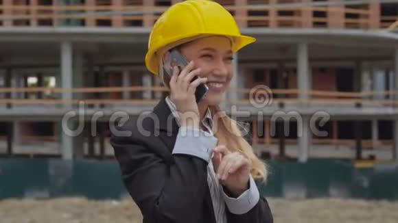 女建筑师在一个建筑工地的背景下兴奋而愉快地在电话里交谈一个女人视频的预览图