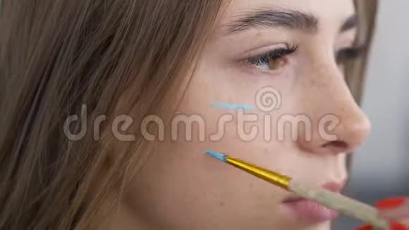 一个年轻漂亮女人的遗像艺术家在女孩的皮肤上用柔软小图标作画视频的预览图