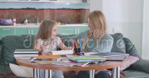 开朗的白种人母女抱在一起就像坐在家里的桌子上一样微笑的父母帮助她的孩子视频的预览图