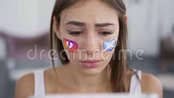 年轻迷人的女人悲伤地看着平板电脑的肖像社交媒体图标画在女孩脸上社会视频的预览图