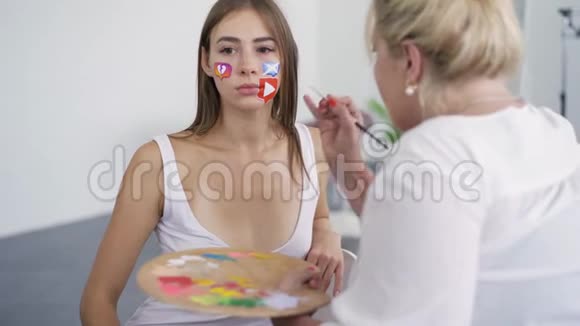 艺术家的肖像画在女孩脸上使用小软笔和调色板身体艺术概念艺术作品视频的预览图