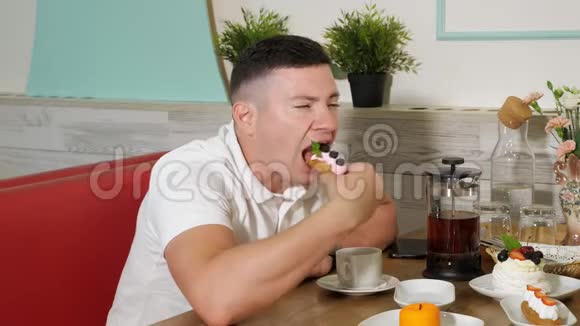 男人在甜店里吃美味的蛋糕和奶油和浆果视频的预览图
