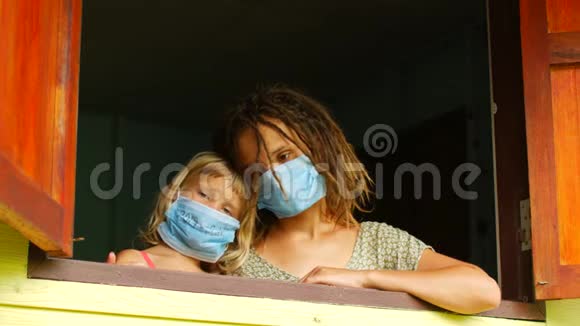 妈妈和女儿戴着防护面具在窗户里传染病检疫病毒COVID19视频的预览图